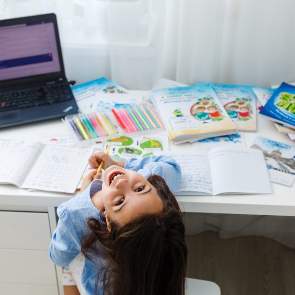 education and school online concept - smiling little student girl with many books at home schooling